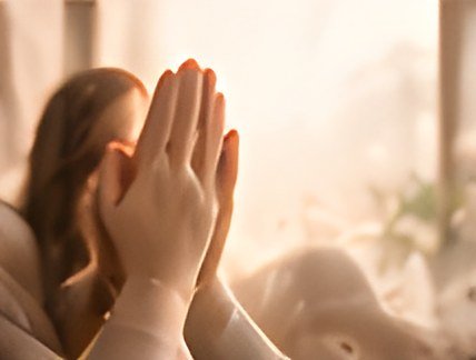 Hands together in prayer in soft light